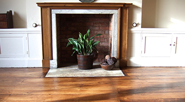 Old elm floor restored in a dining room with fireplace.